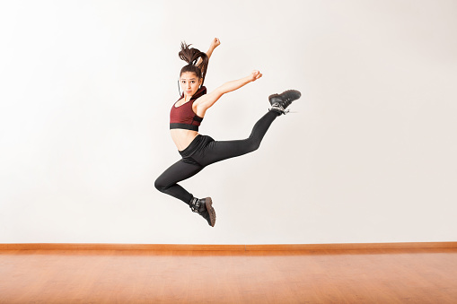 Portrait of a beautiful female jazz dancer jumping in a dance studio and holding a pose