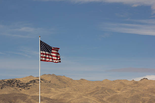 istock USA American Flag with a blue sky background 531000896