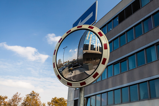 Convex mirror at a street reflecting a barrier entrance in underground garage