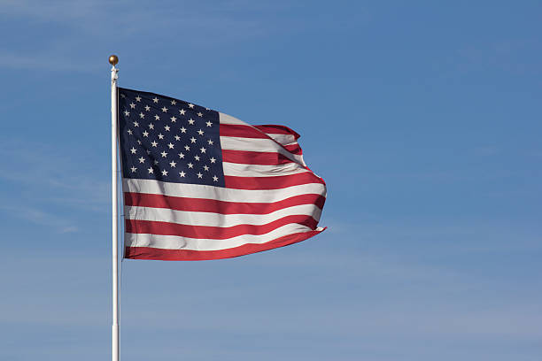 istock USA American Flag with a blue sky background 531001062