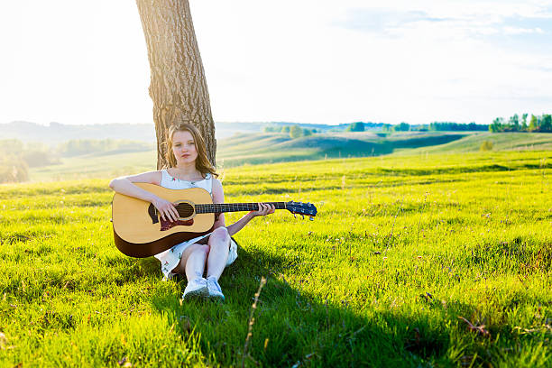 dziewczyna siedząca z gitara akustyczna w polu - sand dune audio zdjęcia i obrazy z banku zdjęć