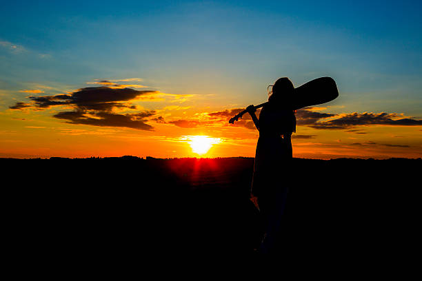 istock Silhouette woman playing guitar in sunset 531003288