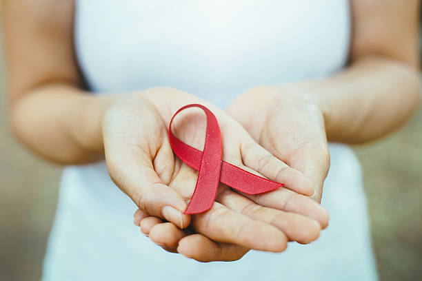 red aids ribbon in hand. red aids ribbon in hand. soft focus on ribbon hiv stock pictures, royalty-free photos & images