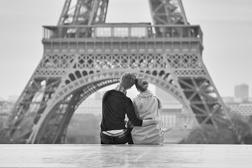 Young romantic couple near the Eiffel tower in Paris, France. Black and white image of dating couple in love