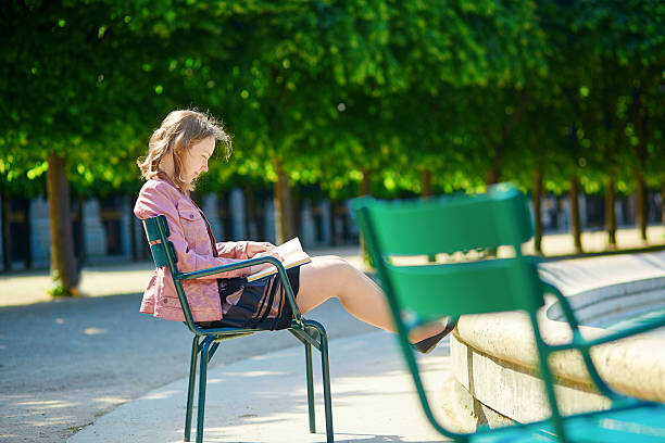 Beautiful young Parisian woman or student reading a book in the Palais Royale garden