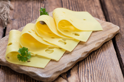 Sliced Cheese (detailed close-up shot) on rustic wooden background