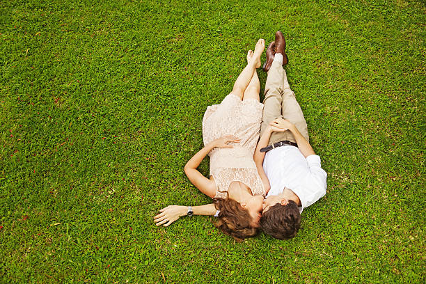 Drone point view  of young couple in love  lying on grass, cuddling and  embracing