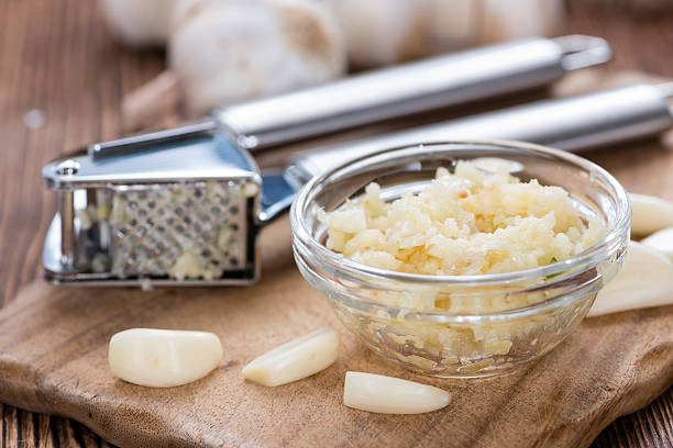 Portion of Crushed Garlic Portion of Crushed Garlic (close-up shot) on wooden background cooking with garlic stock pictures, royalty-free photos & images