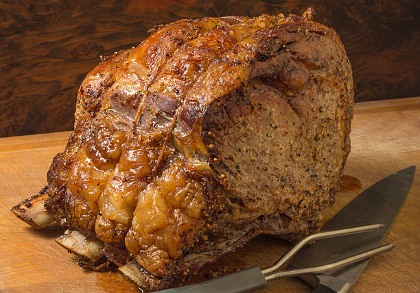 roasted beef prime rib cooked on the bone roasted beef prime rib cooked on the bone and ready to carve into steaks for a great holiday entree prime rib stock pictures, royalty-free photos & images
