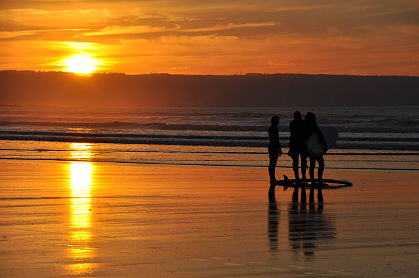 Surfers at sunset stock photo