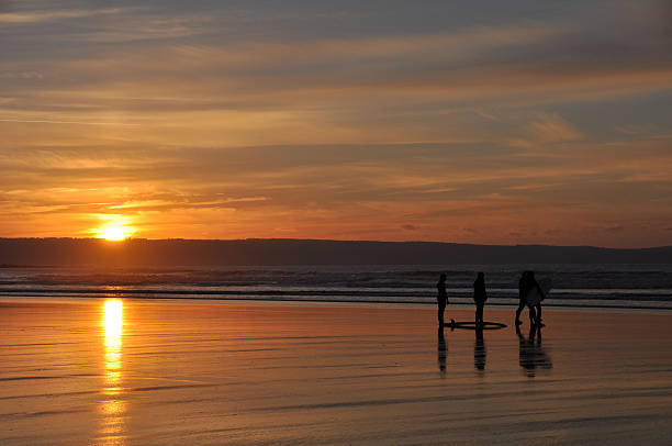 Surfers at sunset stock photo