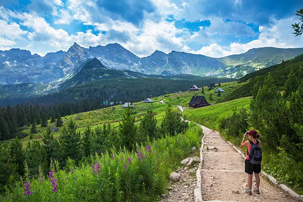 Famale hiker enjoing mountain trip, and taking pictures. Photo taken in Tatra Mountains, Poland.