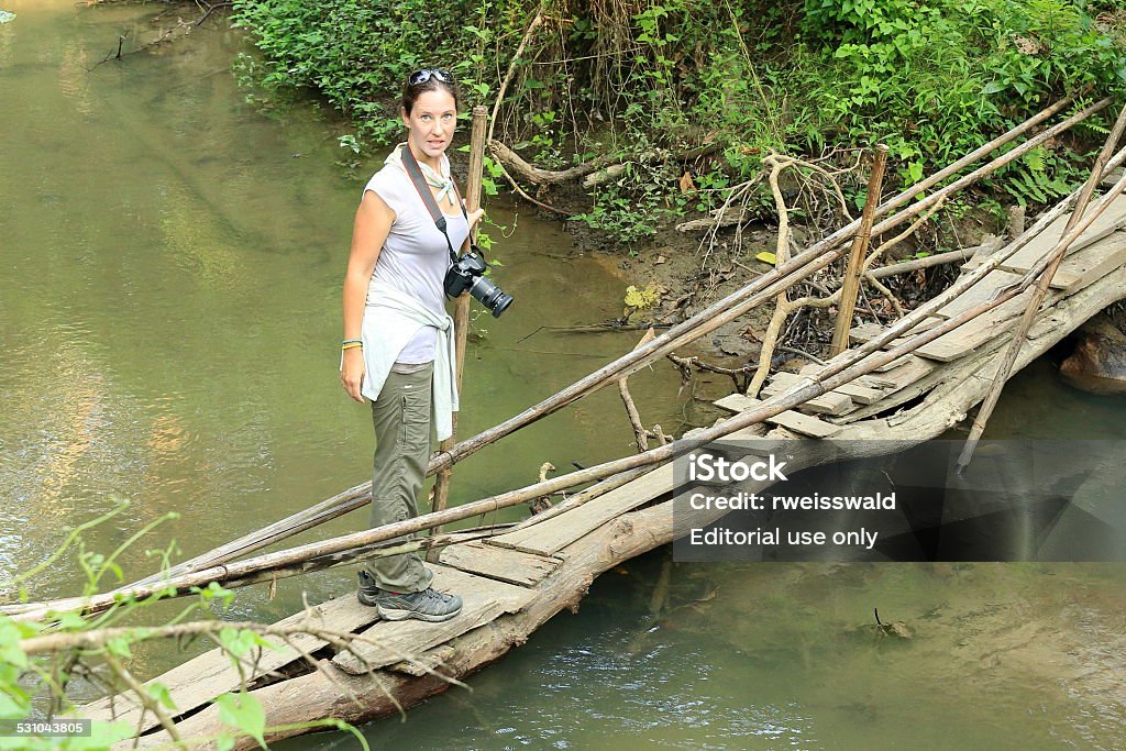 Tourist in the bufferzone off the park. Chitwan-Nepal. 0908 Chitwan, Nepal - October 14, 2012: Tourist crosses a log bridge over a stream in the bufferzone off the Chitwan Nnal.Park on October 14, 2012. Nepal. 2015 Stock Photo