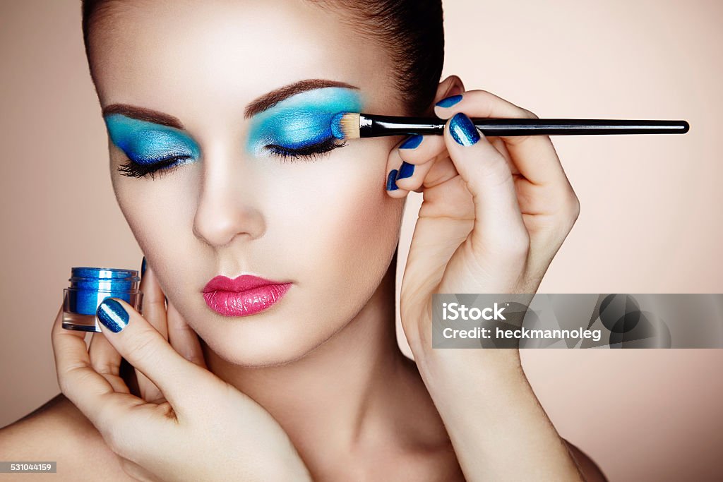 Makeup artist applies eye shadow Makeup artist applies eye shadow. Beautiful woman face. Perfect makeup Cool Attitude Stock Photo