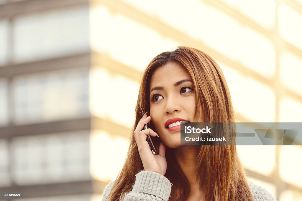 Young asian woman on phone outdoor Close up of beautiful young asian woman talking on phone outdoor at sunset. 2015 Stock Photo
