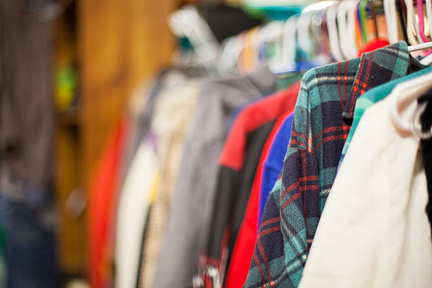 Image of used clothing on racks inside of a thrift store in Portland Oregon. Focus is on the blue and green flannel, and blurs out the remaining background. Thrift store shopping is a growing industry in Portland and many new second hand stores are popping up. Many locals enjoy purchasing second hand clothes for the fashion statement.