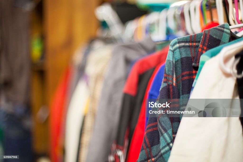 Use Clothing on Discount Racks at Thrift Store Image of used clothing on racks inside of a thrift store in Portland Oregon. Focus is on the blue and green flannel, and blurs out the remaining background. Thrift store shopping is a growing industry in Portland and many new second hand stores are popping up. Many locals enjoy purchasing second hand clothes for the fashion statement. Clothing Stock Photo