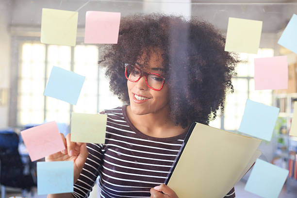 istock Smiling young woman looking at window with sticky notes 531049226