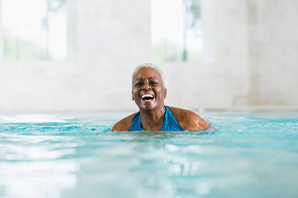 ältere afroamerikanische frau, lachen im swimmingpool - active seniors retirement enjoyment swimming pool stock-fotos und bilder