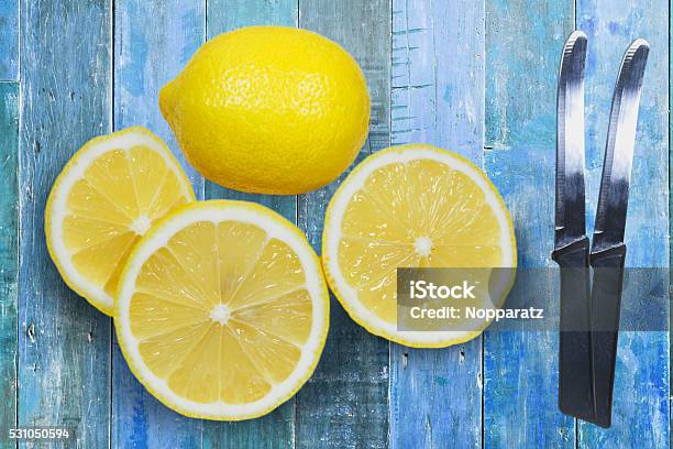 Sliced Lemons With Knife Isolated On Blue Wood Background Stock Photo - Download Image Now
