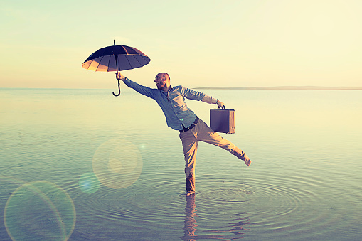 Happy businessman flying with umbrella on salt lake.