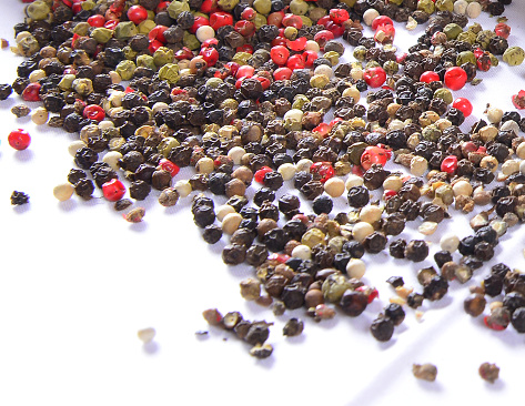 Close up picture of harvested, various red, yellow and black fresh hot chilli pepers on the wooden plate. Nice example variability in sizes, colours, shapes and heat levels of chillies.