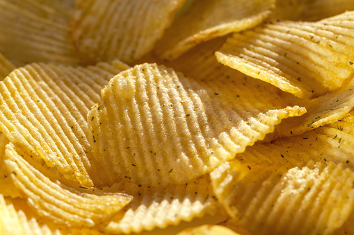 Background of delicious potato chips with spices. Closeup