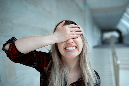 lifestyle shot with blond hair woman having negative attitude, covering hand with her face and having problems.