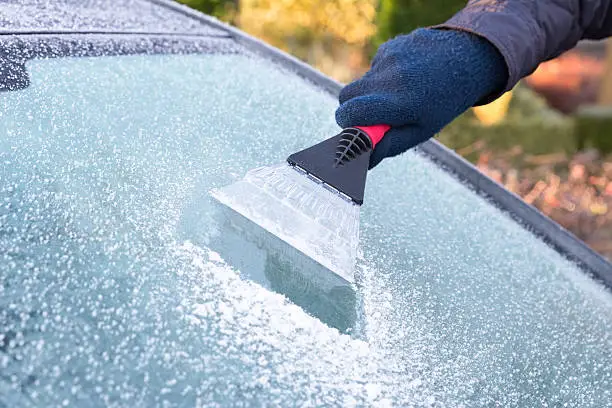 Photo of Hand scratching ice from car window