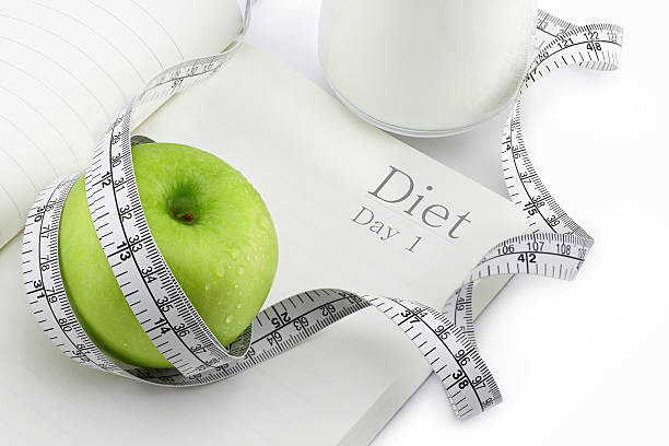 istock Green apple on a notebook and measuring tape, Diet concept. 531058531