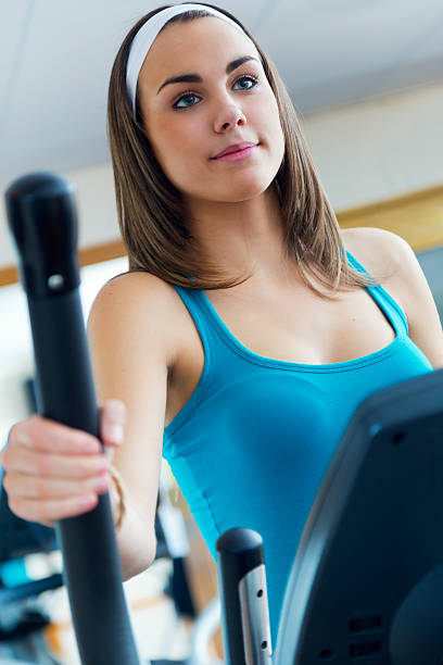 mujer joven con elíptico máquina en el gimnasio. - ellipse elliptical format exercising women fotografías e imágenes de stock