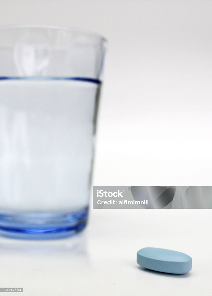 Asprin, pill and glass of water Blue pill in front of water glass on studio shot 2015 Stock Photo