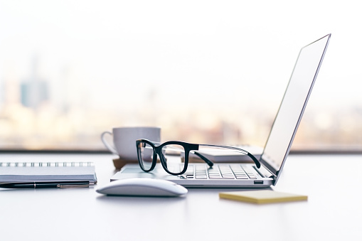 Sideview of office desk with laptop, glasses and other items