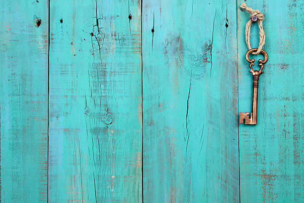 Bronze skeleton key hanging on antique teal blue wooden background Bronze skeleton key hanging by rope on antique teal blue distressed wood door old key stock pictures, royalty-free photos & images