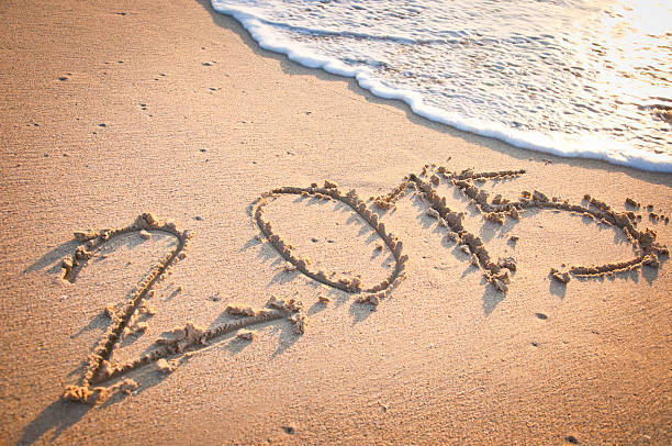 istock Year 2015 written by hand on the sand with wave 531061751