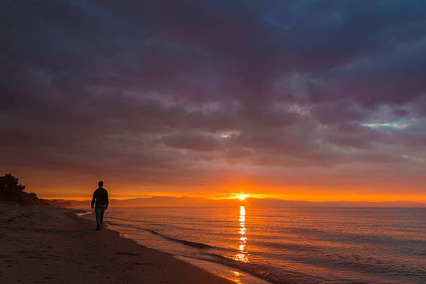 istock man walking on beach in sunrise 531061895