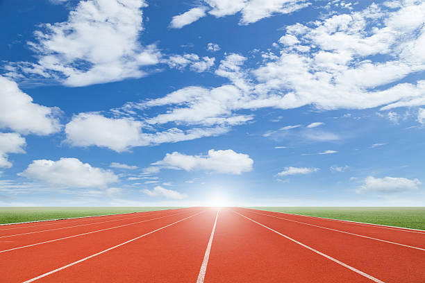 istock Running track with green grass and blue sky white cloud. 531063692