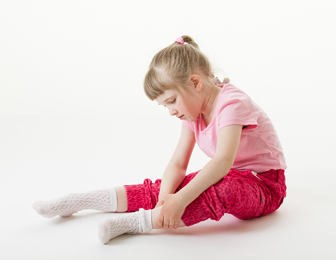 Pretty little girl trying on sock, white background