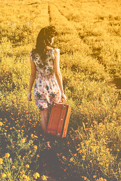 Pretty young woman in a daisy field at sunset. walking away
