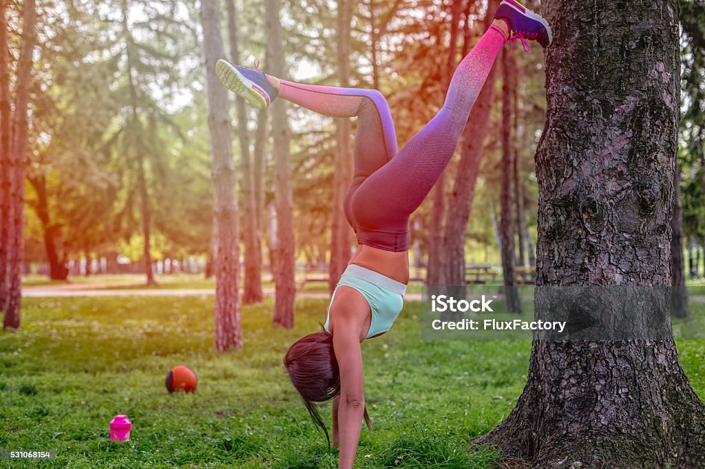 the girl is stretching on a tree girl is having exercise on a tree , recreation in a park , having props lying on a grass 20-29 Years Stock Photo