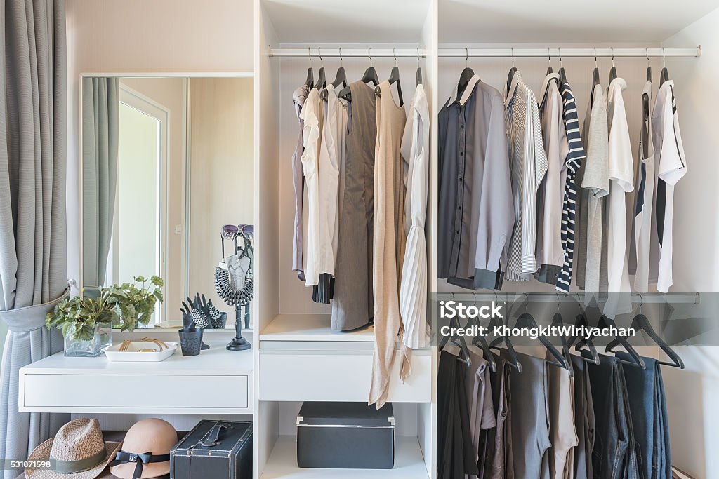 white wardrobe with shirts and pants hanging white wardrobe with shirts and pants hanging on rail Closet Stock Photo