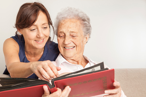 Senior woman shows pictures to her home caregiver