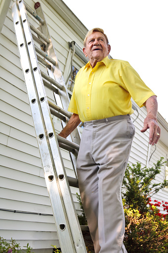 Elderly man looking afar standing on a ladder leaning against house. Image shot with Canon Rebel T6s 24 Megapixel DIGIC 6, 100 ISO, 24-105mm f/4L IS USM lens.