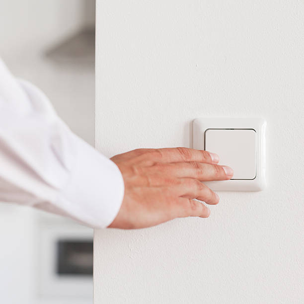 Turning light on Male Hand turning on light on a modern light switch. Shallow DOF. light switch photos stock pictures, royalty-free photos & images