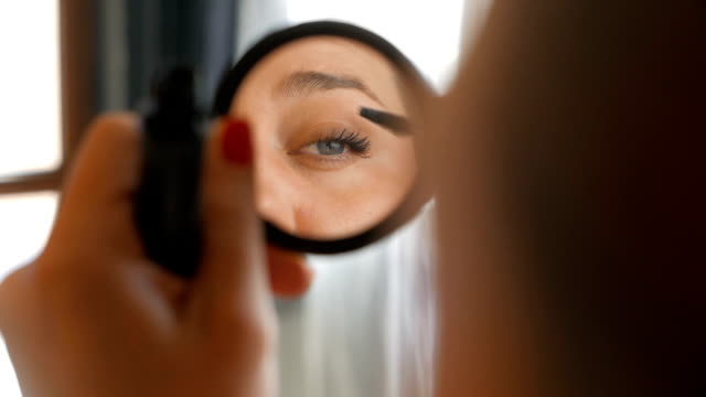 Girl looking at the mirror applying make up