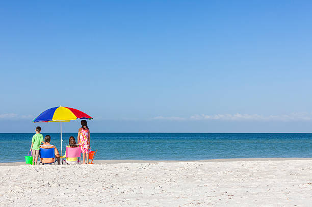 istock Family Alone on Empty Beach With Umbrella 531084707