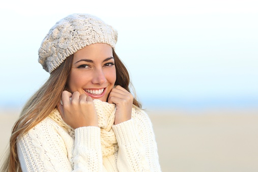 Woman smile with a perfect white teeth in winter with the beach in the background