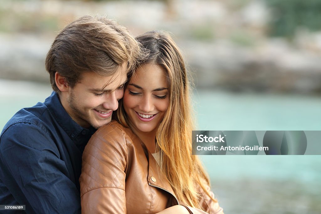 Couple cuddling affectionate on the beach Couple cuddling affectionate on the beach in winter with the sea in the background Couple - Relationship Stock Photo