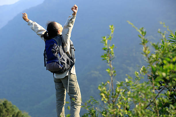 istock cheering woman hiker open arms at mountain peak 531098347