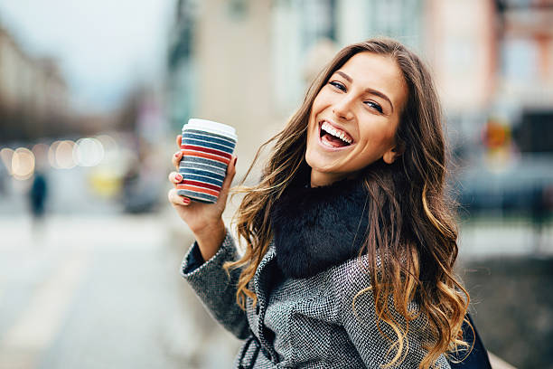 giovane donna con una tazza di caffè all'aperto sorridente - long hair beauty adult attractive female foto e immagini stock